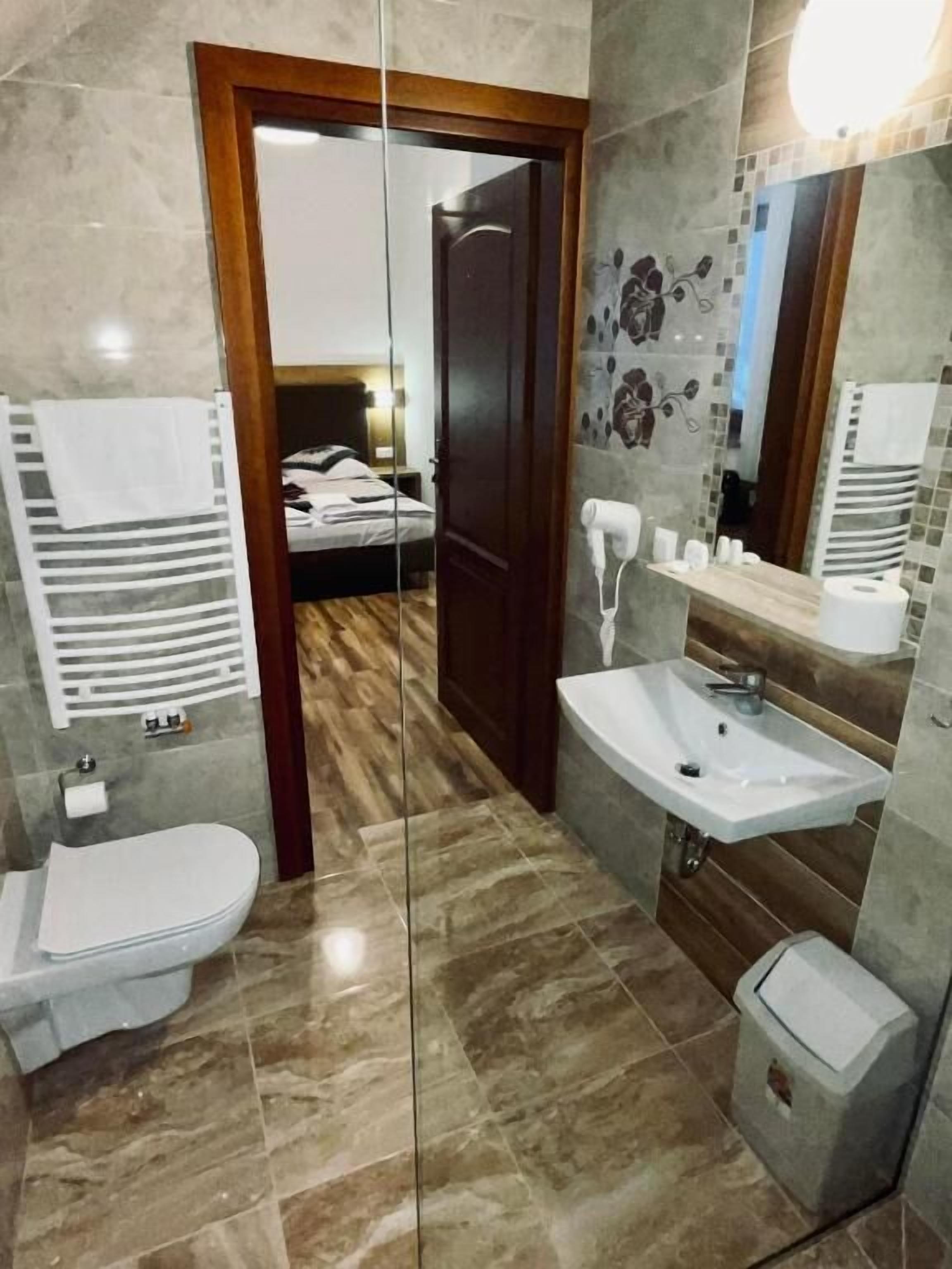 A modern bathroom with a vanity, sink, and toilet. There is a shower area with a glass door and a mirror above the sink.