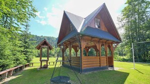 A wooden cabin with a swing set and a small gazebo in a lush, green setting. - Pod Tatrami (Bukowina Tatrzanska)