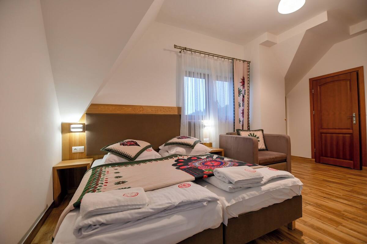 Un dormitorio con cama, una silla, una puerta de madera y una ventana con cortinas.