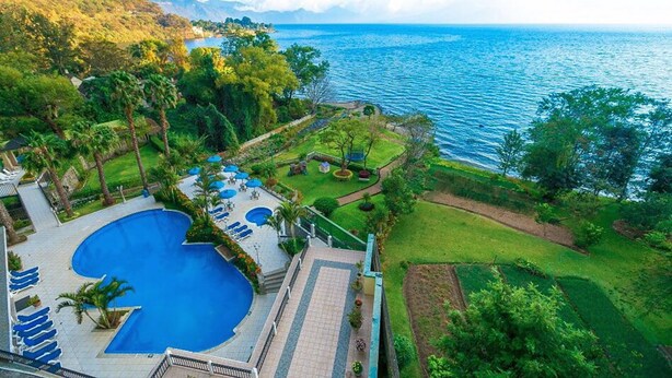 Ein Resort mit großem Pool, gepflegter Rasenfläche und Meerblick.