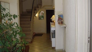 Un pasillo con una escalera, una planta y una pequeña mesa con una lámpara.