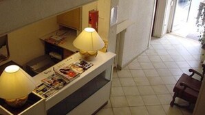 Una recepción con dos lámparas, una mesita con revistas y una silla en la esquina.