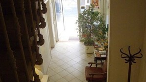 Un pasillo con piso de baldosas que conduce a una habitación con una silla y una planta.