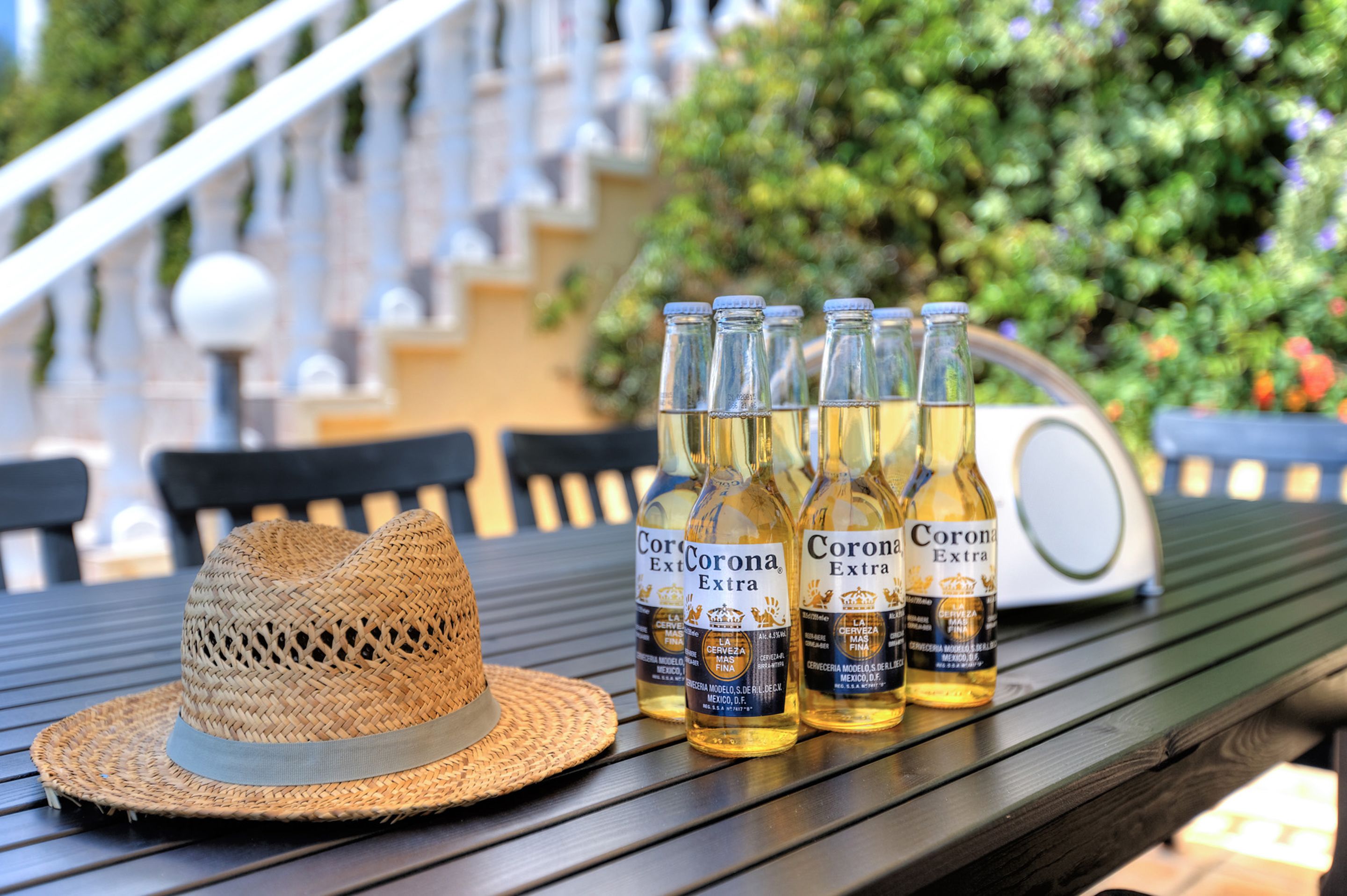 A straw hat and four bottles of Corona Extra beer on a wooden table.