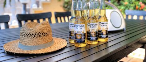 A straw hat and four bottles of Corona Extra beer on a wooden table.