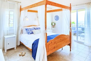 A four-poster bed with a canopy, a bedside table, and a view of the outdoor area.