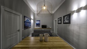 Un pasillo con una mesa de madera, dos jarras de cerámica, un televisor y obras de arte en las paredes.
