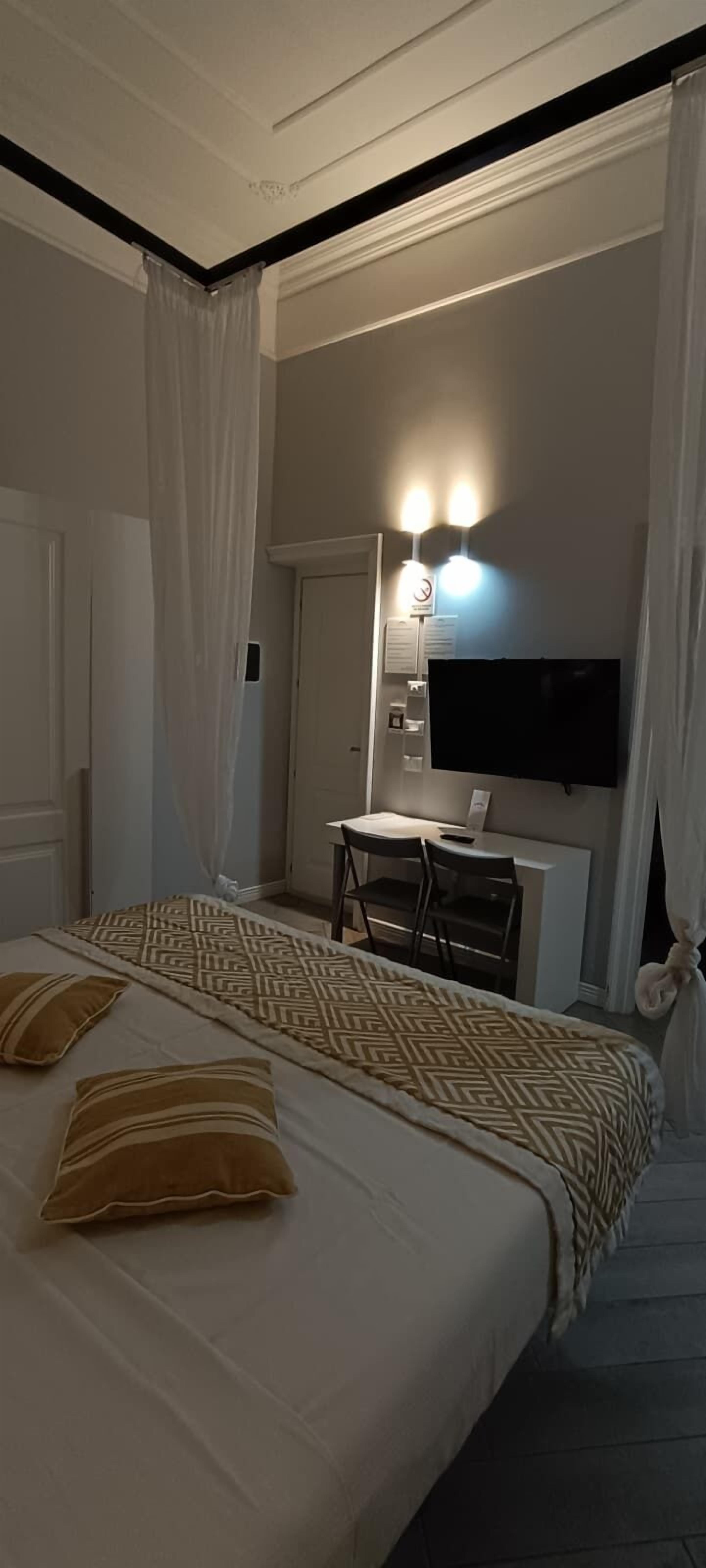 Un dormitori amb un llit, una taula de treball i una televisió.