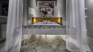 A bed with a patterned bedspread, a wooden headboard, and bedside lamps. - Suite del Ponte Normanno (Palermo)