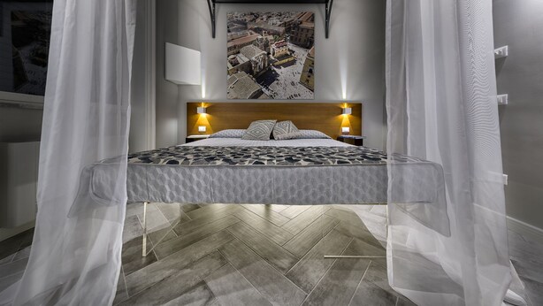 Una cama con colcha estampada, cabecera de madera y lámparas de noche.