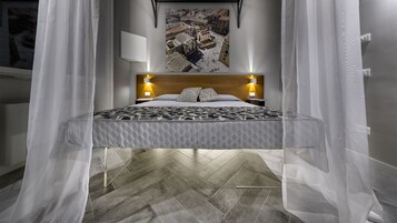 Una cama con colcha estampada, cabecera de madera y lámparas de noche.
