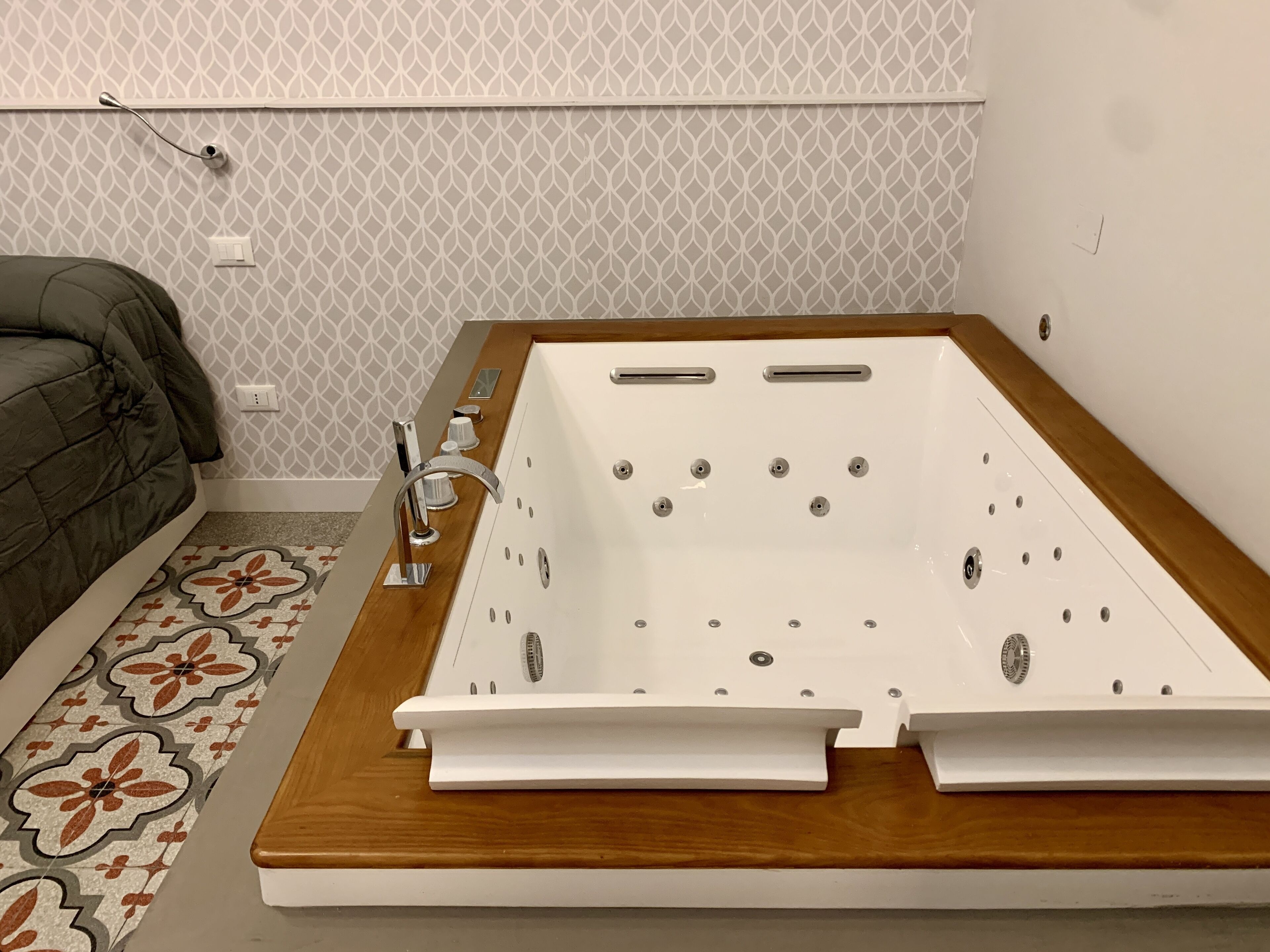 A modern bathroom with a freestanding bathtub, a wooden vanity, and a patterned floor.