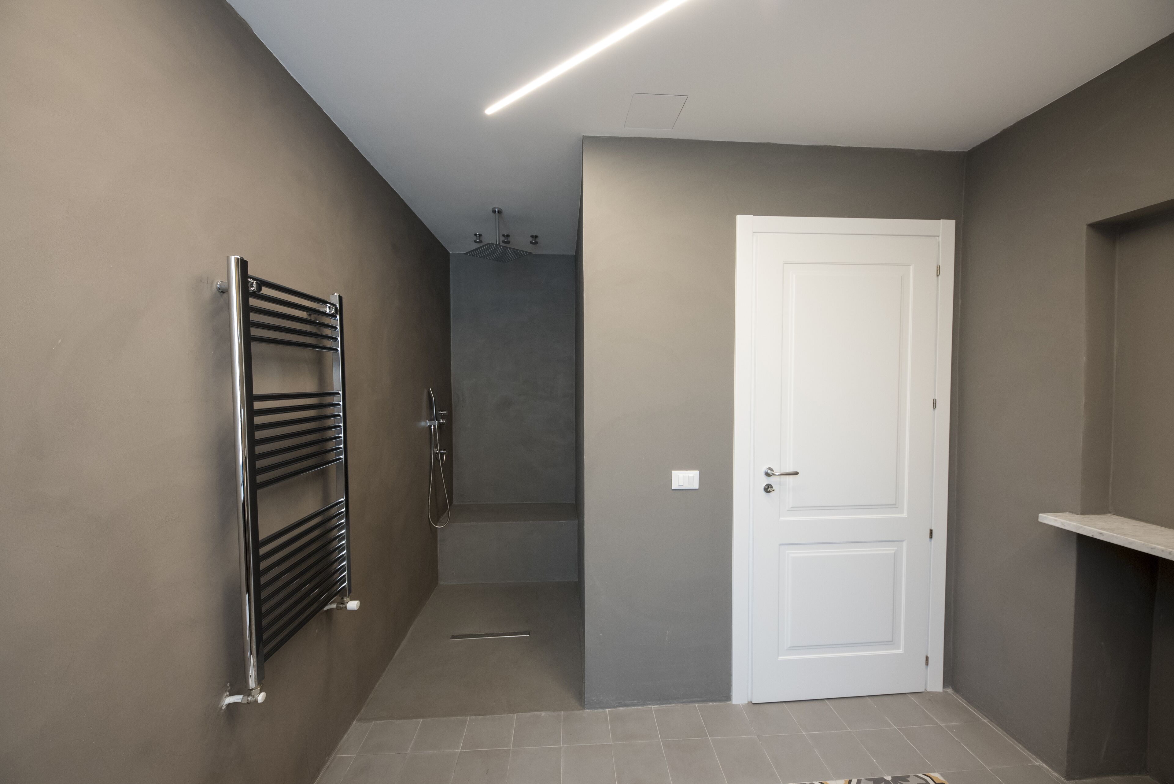 A bathroom with a towel rack, a shower, and a door.