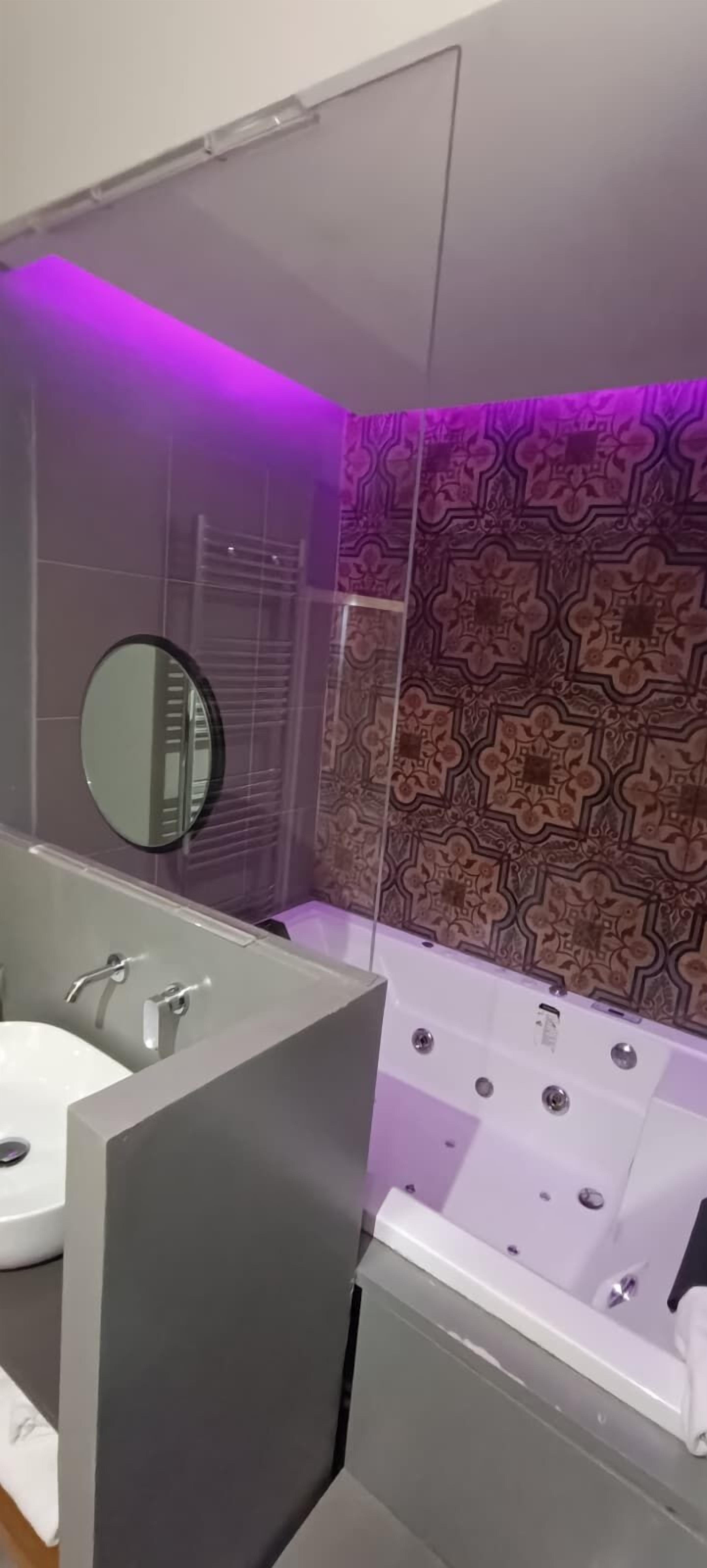 A modern bathroom with a large bathtub, a double sink, and a mirror.