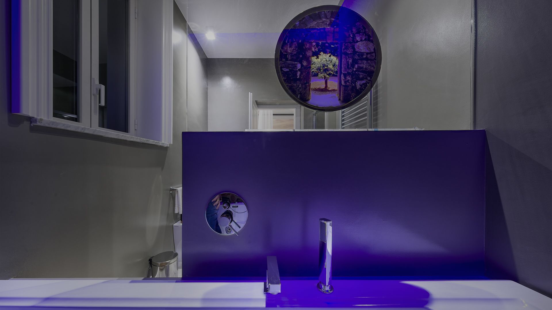 Un baño con un lavamanos blanco, un espejo y un adorno circular en la pared.