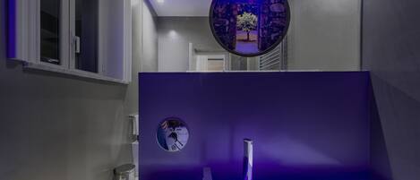 A bathroom with a white sink, a mirror, and a circular decorative item on the wall.