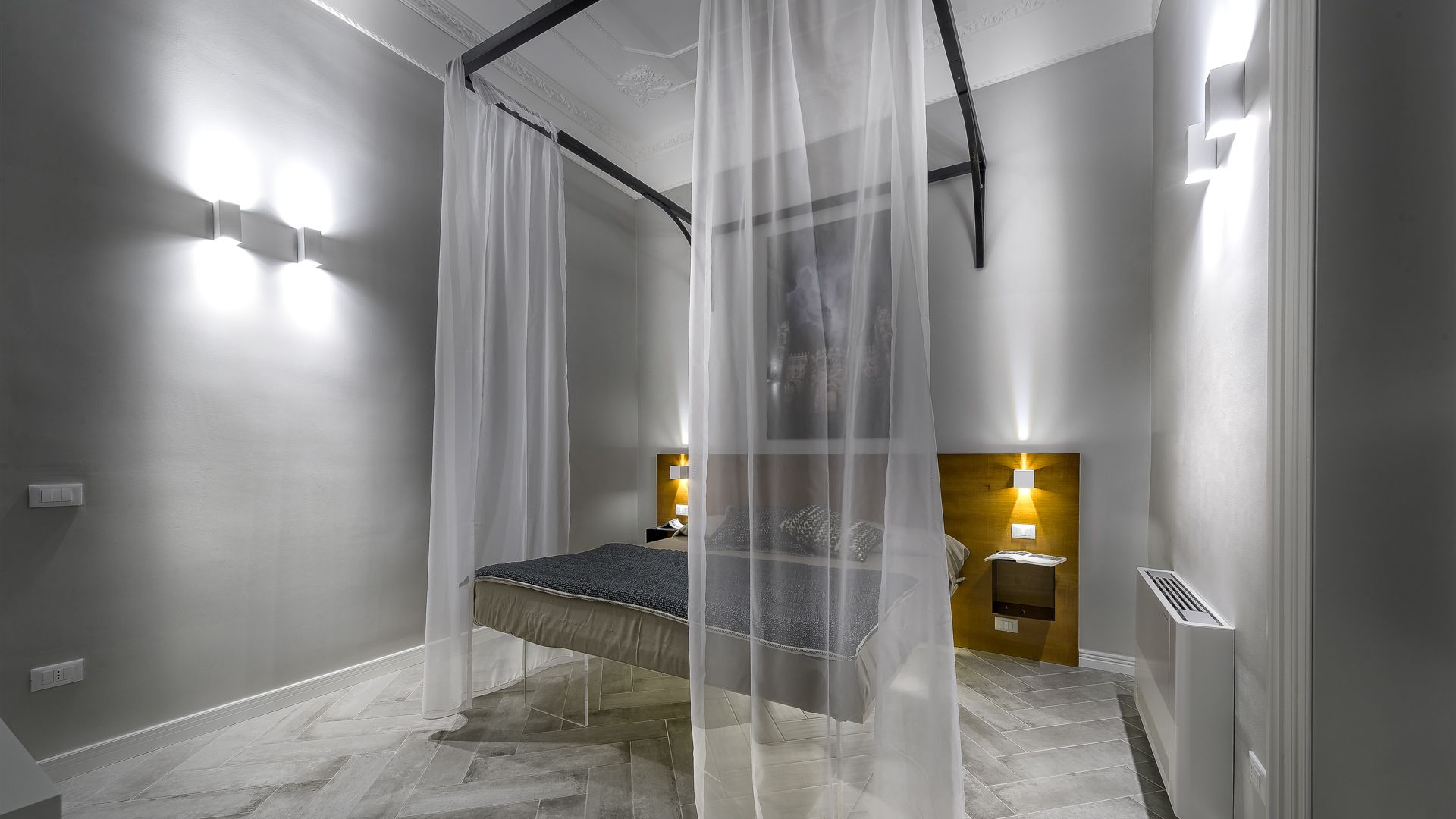 A modern bathroom with a bed, a shower area, and a vanity with a mirror and light fixture.