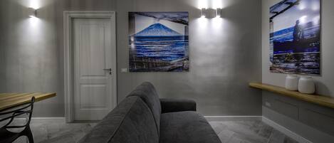 A modern hallway with a grey sofa, a wooden table, and two wall-mounted light fixtures.