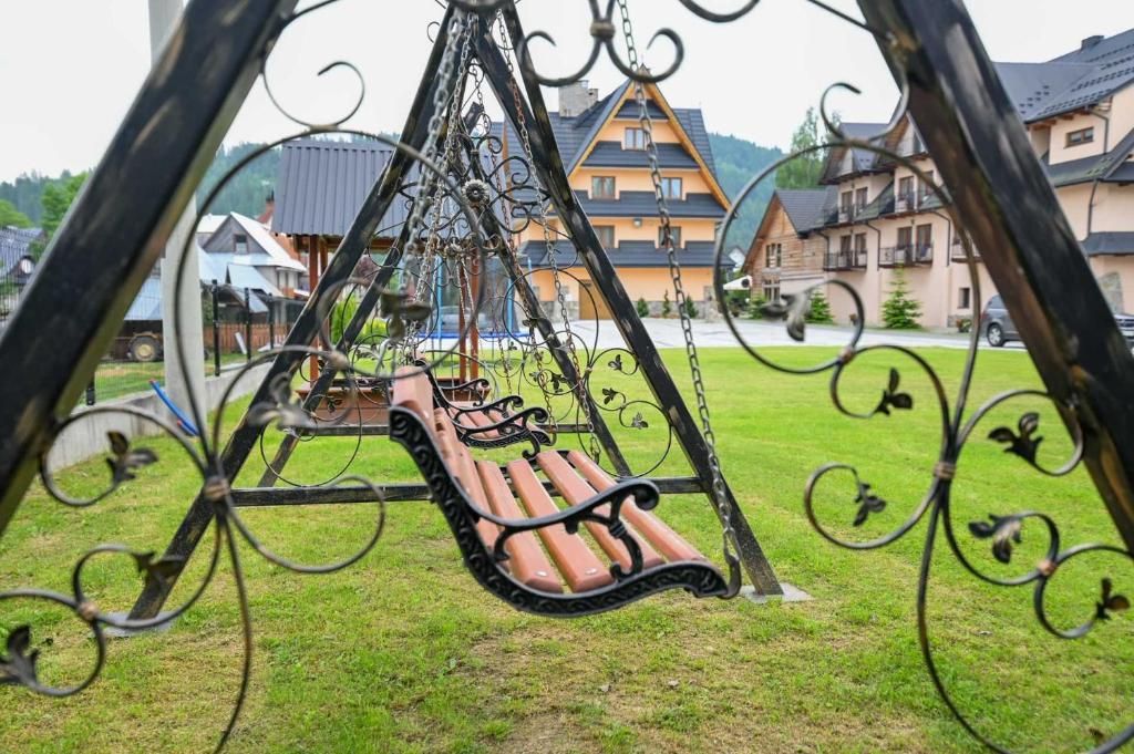 Un columpio con asiento tipo banca, rodeado por una valla de metal con detalles decorativos.