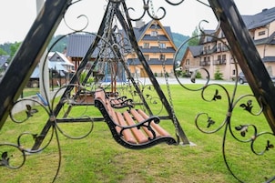 Eine Schaukel mit Sitzbank, umgeben von einem Metallzaun mit Verzierungen.