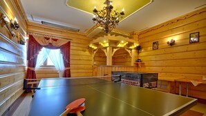 Una mesa de ping pong en una habitación con paredes de madera y un candelabro.