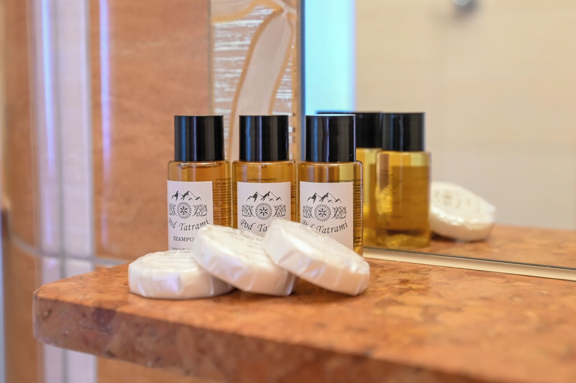 Quatre bouteilles de shampoing Pod Tatrami et trois savons sur un comptoir en marbre.
