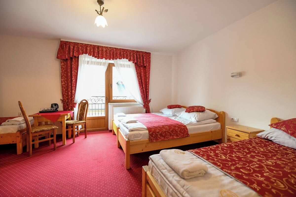 Une chambre d’hôtel avec deux lits, un bureau, une chaise et une fenêtre avec des rideaux.