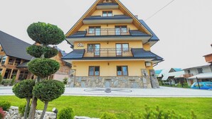 Un edificio de varios pisos con fachada amarilla, con el número 59A, que presenta balcones y una base de piedra.