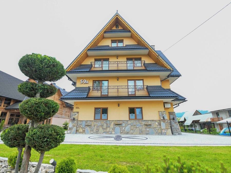 Un immeuble à plusieurs étages, avec une façade jaune, portant le numéro 59A, doté de balcons et d’un socle en pierre.