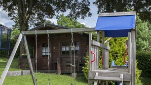 A wooden play structure with a swing and a climbing ladder in a grassy area. - Pension Haus Brieden (Winterberg)