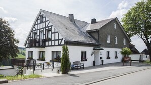 A traditional half-timbered building with a balcony, a bench, and a sign indicating it is a guesthouse. - Pension Haus Brieden (Winterberg)