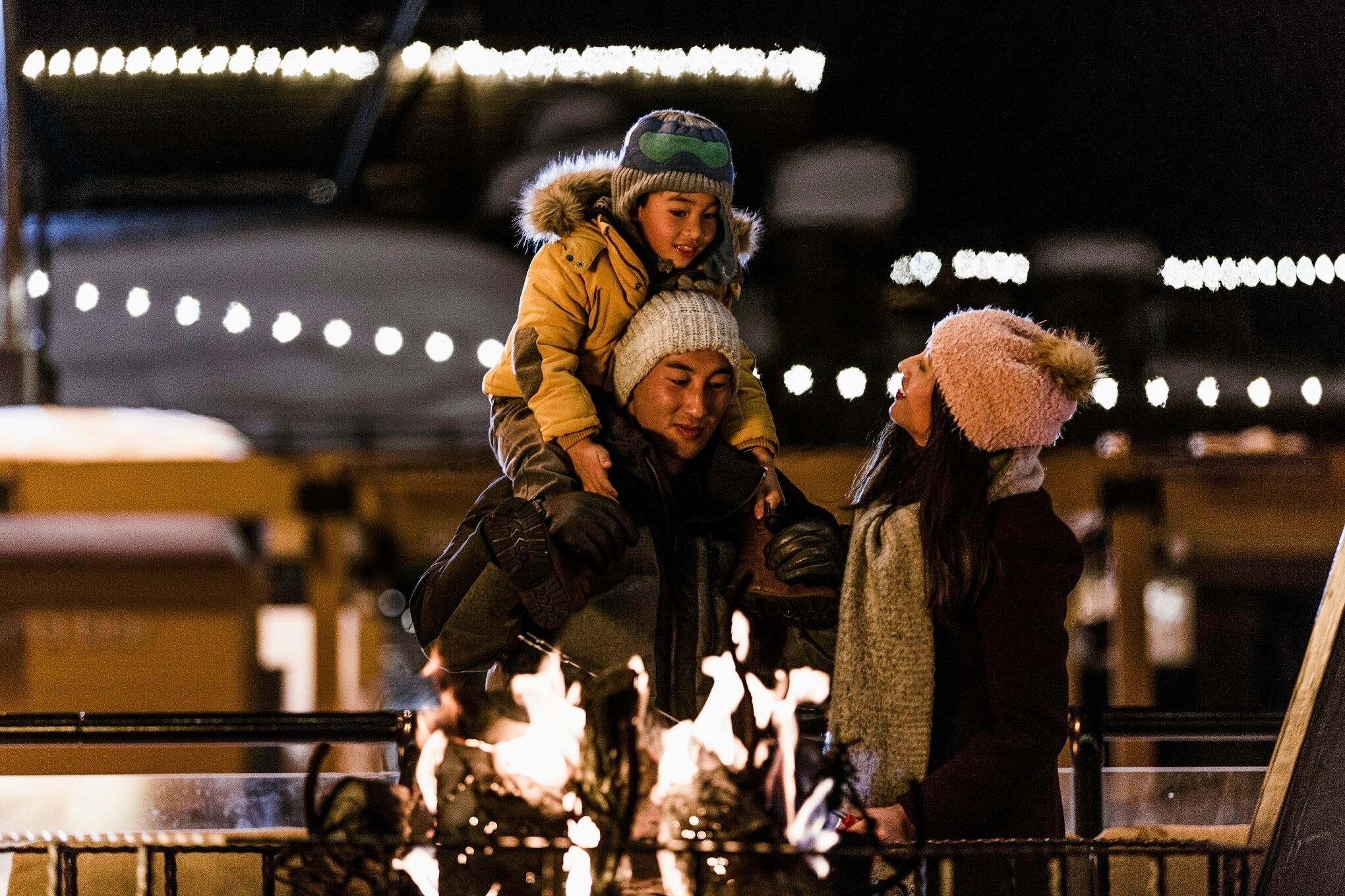 Iemand draagt een ander persoon op zijn schouders, met een hek en een vuur op de voorgrond.