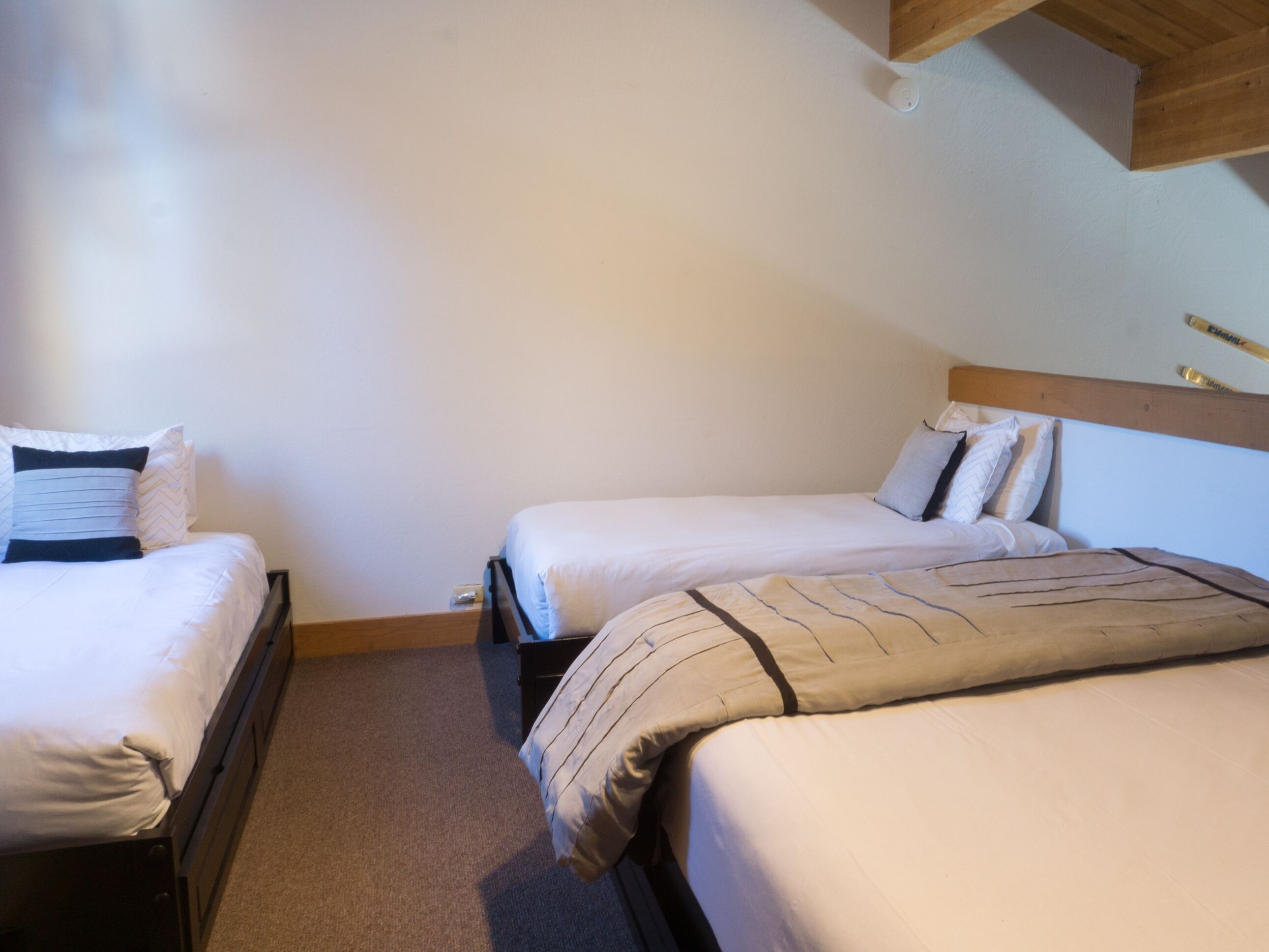 Una habitación con dos camas individuales, cada una con cabecera de madera y ropa de cama blanca.
