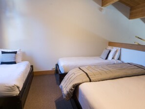 A room with two single beds, each with a wooden headboard and white bedding.