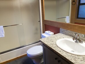 A bathroom with a white toilet, a sink with a granite countertop, and a mirror above the sink.