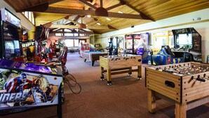 A spacious indoor area with wooden ceiling beams, various arcade games, and a foosball table. - 3178 Aspen Grove (Truckee)