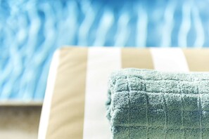 A close-up of a striped towel on a chair by a pool. - Villa Chiara (Kissonerga)