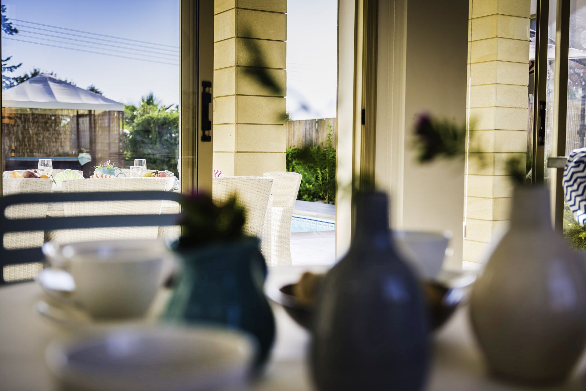 Un coin repas avec une table mise pour deux personnes, une chaise et un vase.
