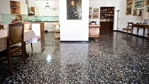 Une pièce spacieuse dotée d’un plancher ciré, d’un coin repas avec une table et des chaises, d’un coin cuisine avec des placards et un évier, ainsi que d’une bibliothèque remplie de livres.