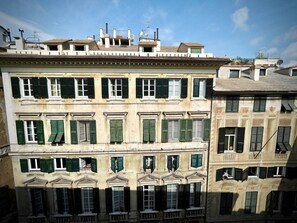 A multi-story building with green shutters, balconies, and a classic architectural style.