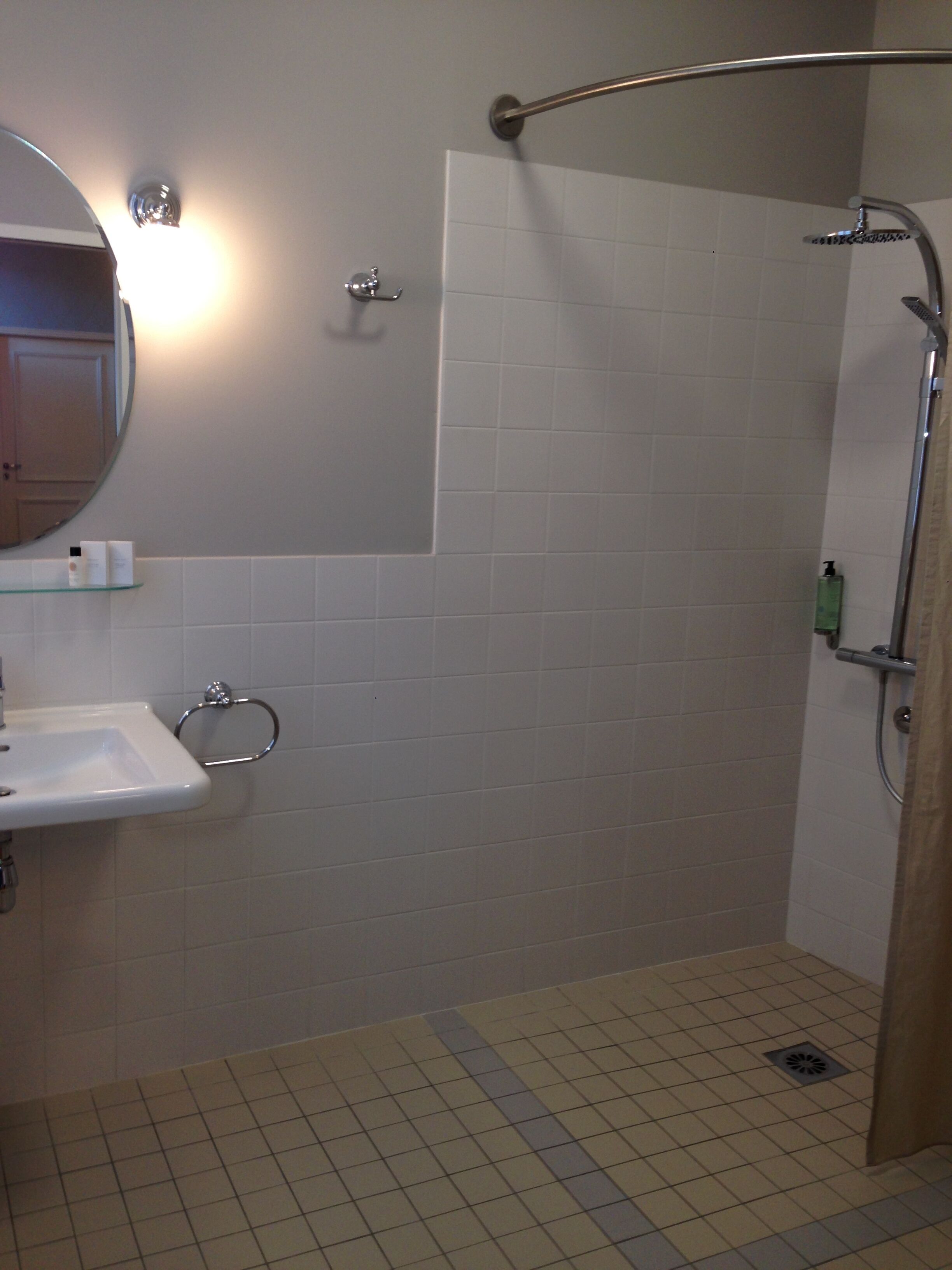 A bathroom with a sink, mirror, and shower.