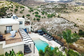 A modern villa with a pool, outdoor seating, and a scenic hillside view. - Villa Christina (Paphos)