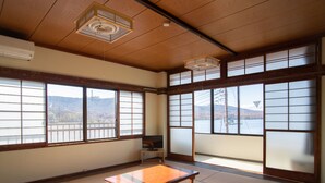 Une pièce de style japonais traditionnel, avec un sol recouvert de tatamis, des portes coulissantes en papier de riz (shoji) et une vue sur un paysage montagneux.