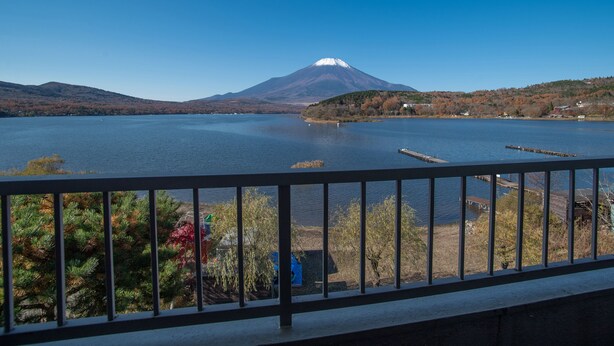 Une vue sur un lac, avec une montagne en arrière-plan, une jetée et une rambarde au premier plan.