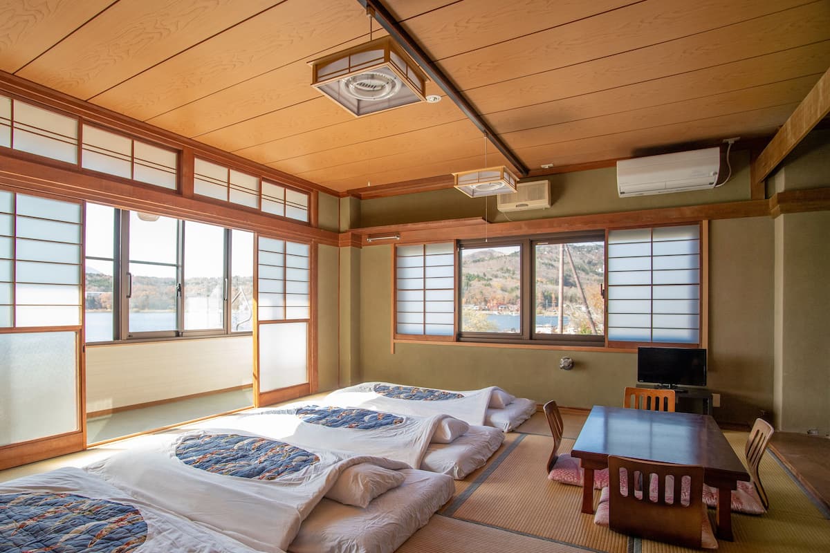 Ein traditioneller japanischer Raum mit Tatami-Bodenbelag, einer Futon-Liege, einem Holztisch und Shoji-Schiebetüren.