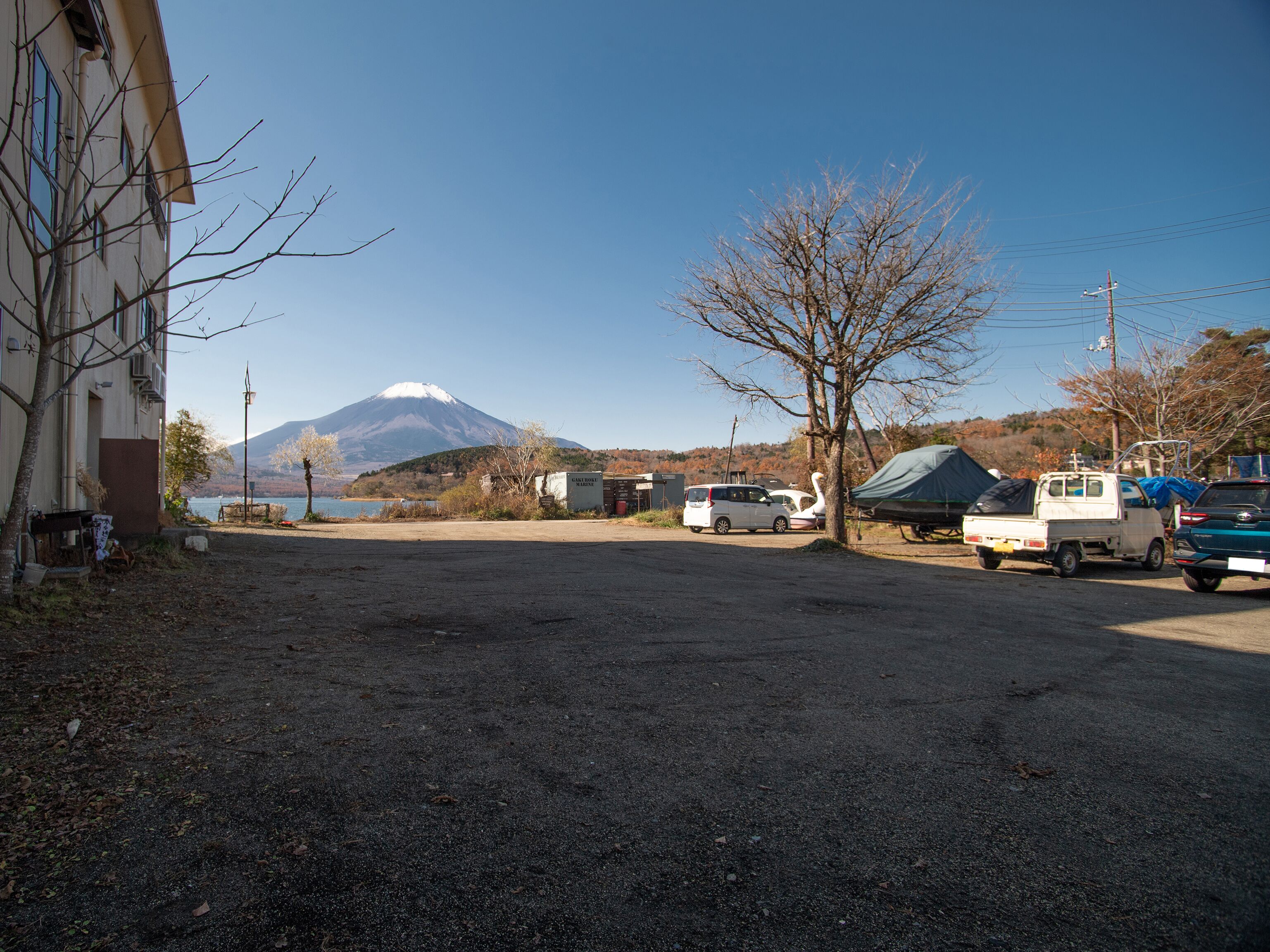 Un estacionamiento con vehículos, un edificio y una montaña al fondo.
