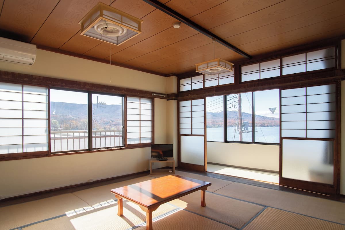 Ein traditioneller japanischer Raum mit Tatami-Böden, verschiebbaren Shoji-Türen und Blick auf eine Berglandschaft.