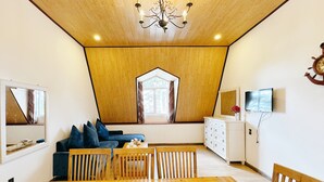 A dining area with a wooden table, chairs, and a fruit bowl. - TTR Joy Apart Hotel (Xuan Huong - Da Lat)