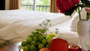 A hotel room with a bed, a window with curtains, a vase with flowers, and a fruit plate. - TTR Joy Apart Hotel (Xuan Huong - Da Lat)