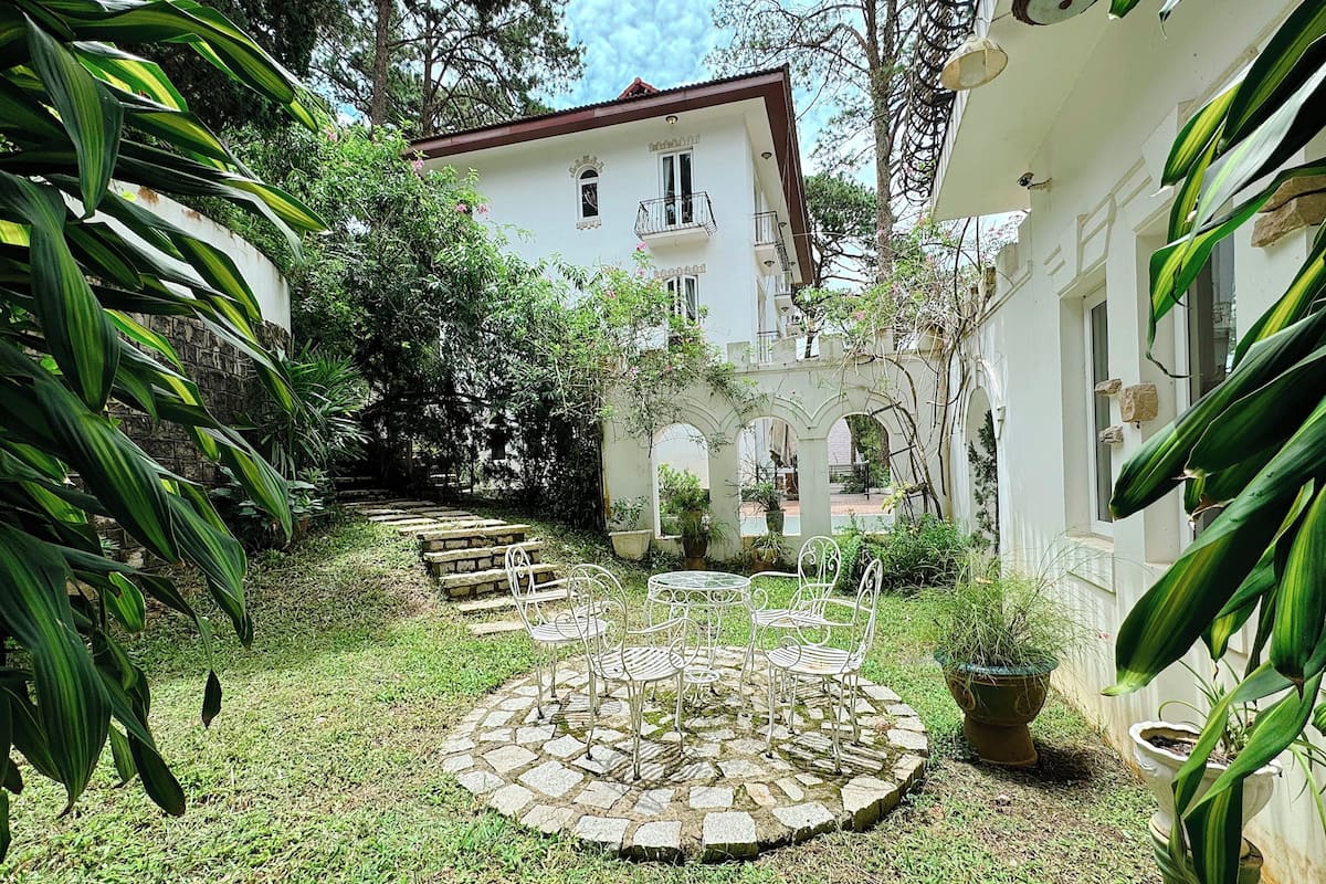 Un jardín con un camino de piedra que conduce a una zona circular de estar con sillas.